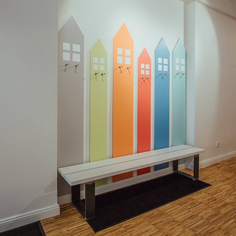 Garderobe aus bunten Holzhäusern über einer Bank